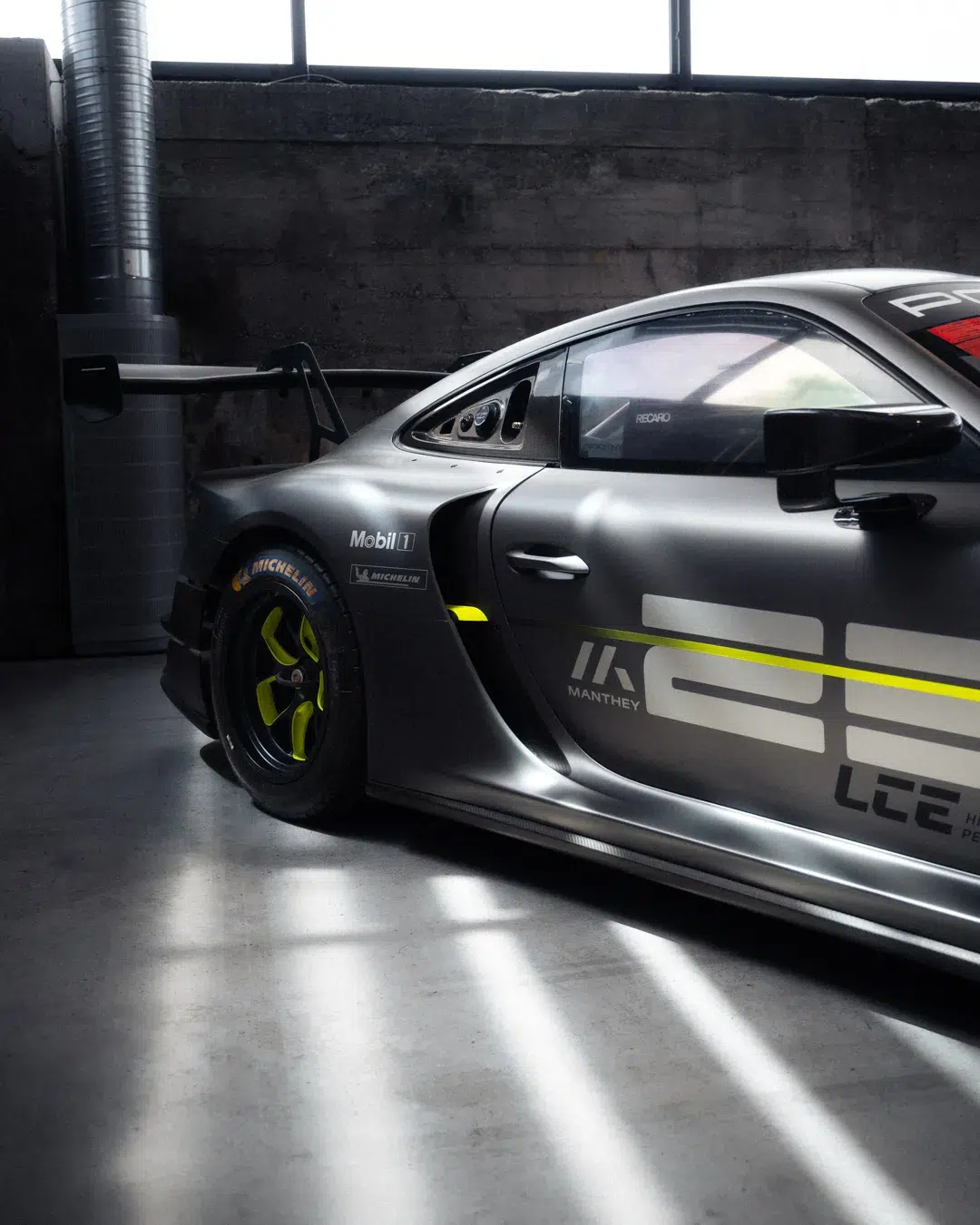 Seitenansicht des grauen Porsche GT3 R mit neongelben Akzenten auf dem MYLE 24